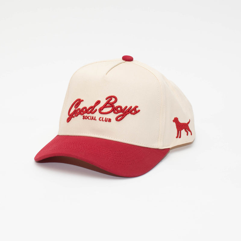 Angled view of the Crimson hat with a cream crown, red brim, Good Boys Social Club embroidery, and side dog silhouette.